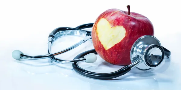 A stethoscope and an apple with the heart drawn on it.